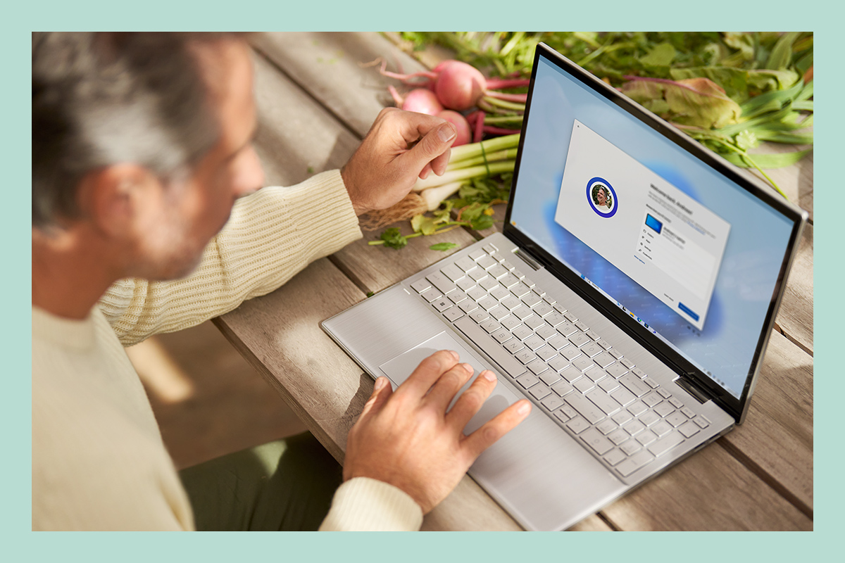 A man is using a laptop, setting up existing files, apps, and default configurations via Windows 11.