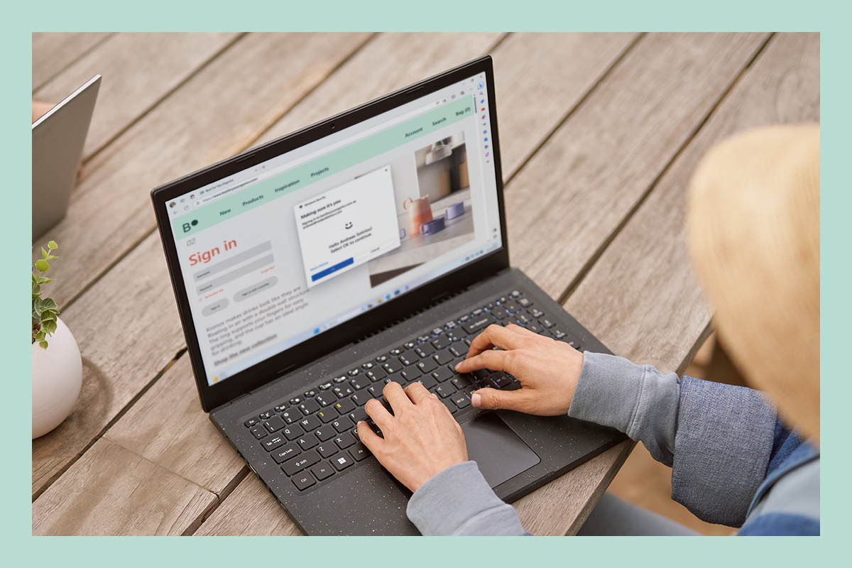 A woman is using a laptop and utilizing Windows 11's built-in security.